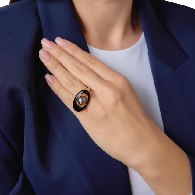 This striking vintage ring centers on a lustrous Tahitian pearl measuring approximately 9.69mm, displaying a rich, dark...