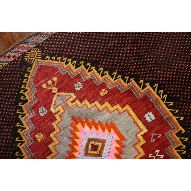 One of a kind corridor size Turkish Kars rug from the 20th century. A dark brown geometric field with saturated colors in...
