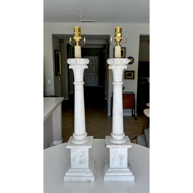 Pair of Large Italian Neoclassical style carved column form alabaster table lamps, featuring elegant fluted shafts and...