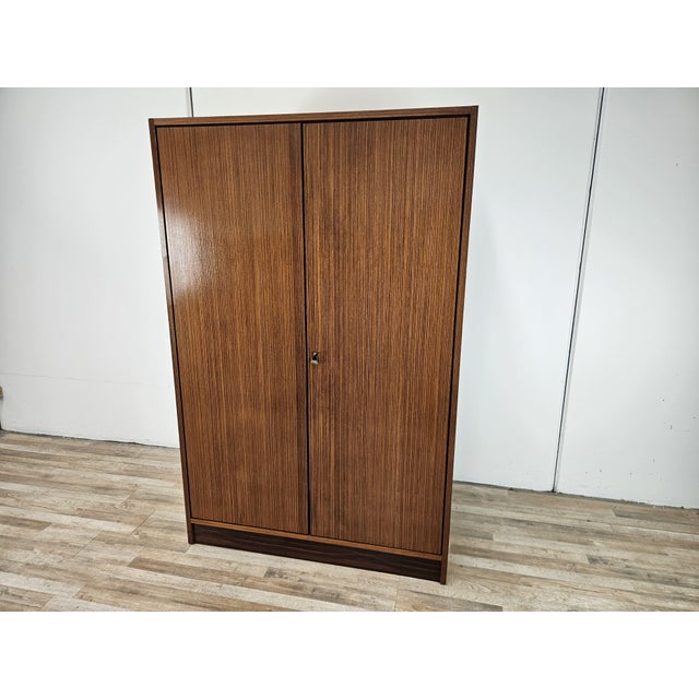 An elegant vintage wardrobe from the 1960s, featuring a simple and refined design typical of mid-20th-century Italian...