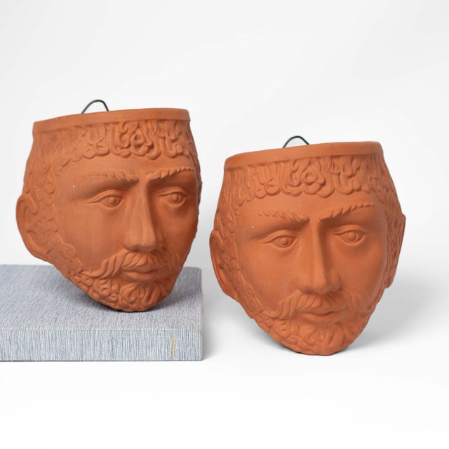 A striking pair of vintage terracotta wall planters sculpted in the form of mythological Greek or Roman male god faces....