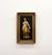 A decorative wall plaque featuring a raised classical female figure finished in warm gilt tones against a black textured...