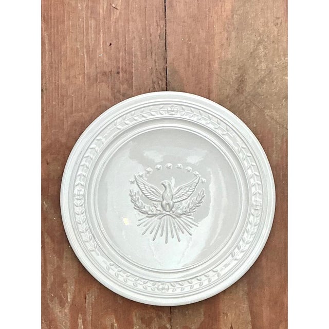 A vintage Italian ceramic platter centered on a raised eagle with outstretched wings. A laurel wreath and five stars frame...