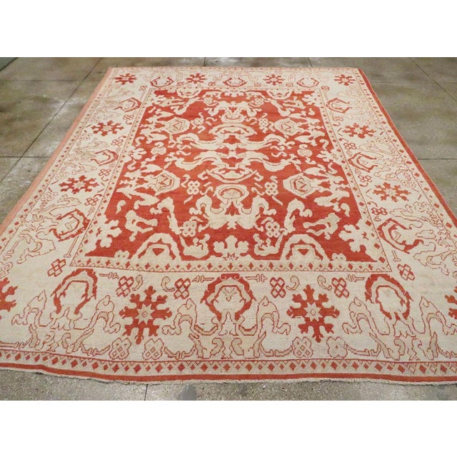 An antique Turkish Oushak room size carpet. Cloud bands are everywhere on the Turkey red ground of this western Anatolian...