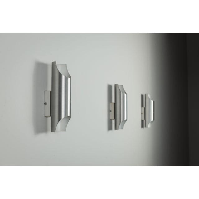 This set of three vintage aluminium wall lamps is a striking example of sculptural, architectural lighting design. Their...