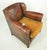 Vintage dark brown leather studded club chair made in France. It has a plush amber cushioned seat, studded details, and...