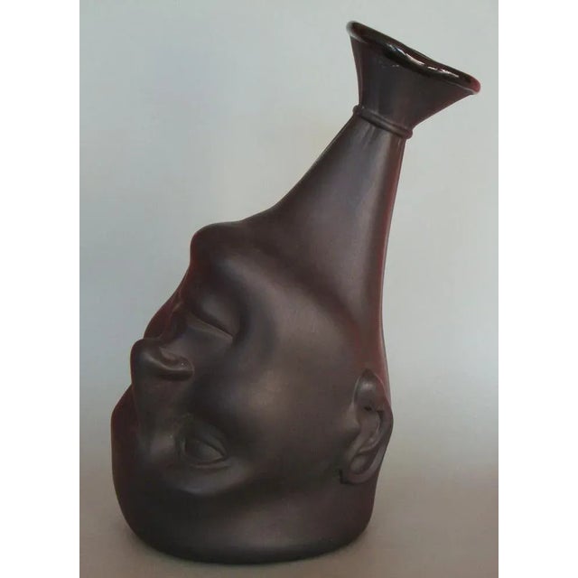 The vase showcases the artistic interpretation of a man's head, capturing its distinctive features and form. The use of...