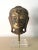 An gilt and lacquered wood Buddha head with displayed on a metal and Lucite stand. stunning presence with its refined...