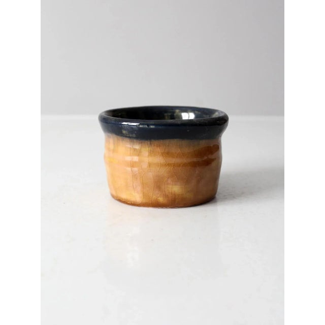 This vintage studio pottery cachepot features a captivating glaze that transitions from warm golden tones to deep, inky...