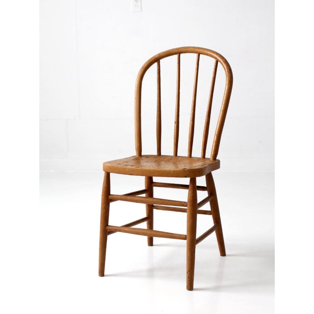 Early 20th century Windsor bow back chair with a warm mustard painted finish and a classic farmhouse silhouette. The...