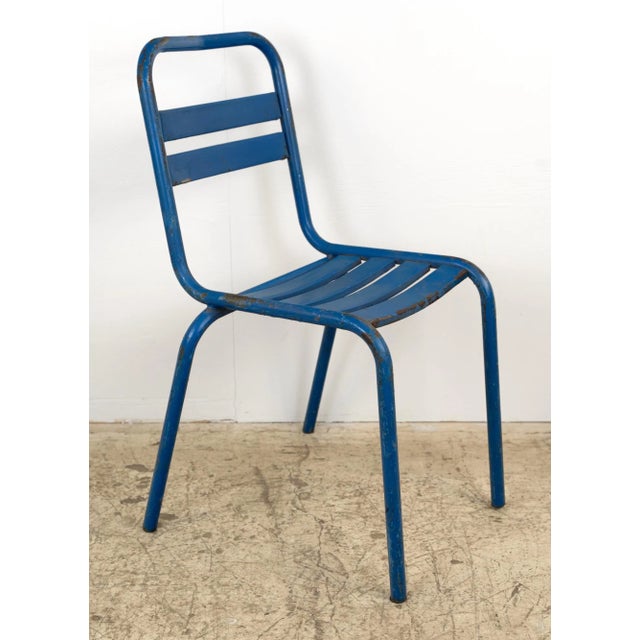 Vintage European Tolix style blue steel chair featuring a rectangular slatted backrest with a cutout at the top and four...
