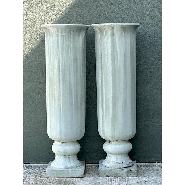 This pair of tall urns embraces a classic neoclassical silhouette, each cylindrical body finely fluted with narrow...