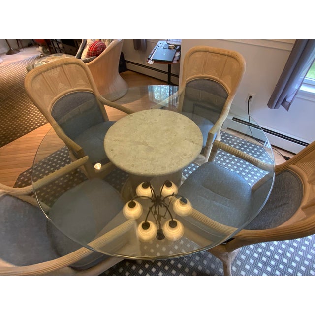 20th century Cast stone, rattan wrap column pedestal table. Glass top sits on base. Four rattan wrap arm chairs. In the...