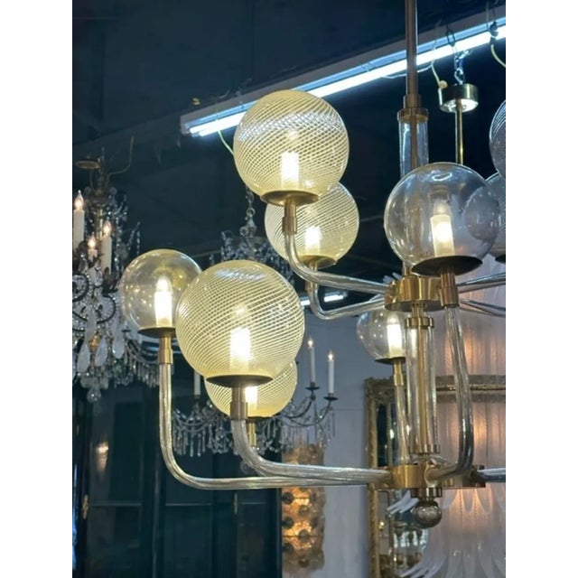 Modern Murano glass and brass globe chandelier. Lovely pattern on the globes along with beautiful glass arms and brass...