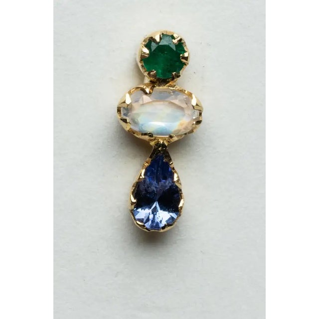 An elegant trio of gemstones comprise this pair of bezel-set stud earrings in 18K gold. The top stone is a round, faceted...