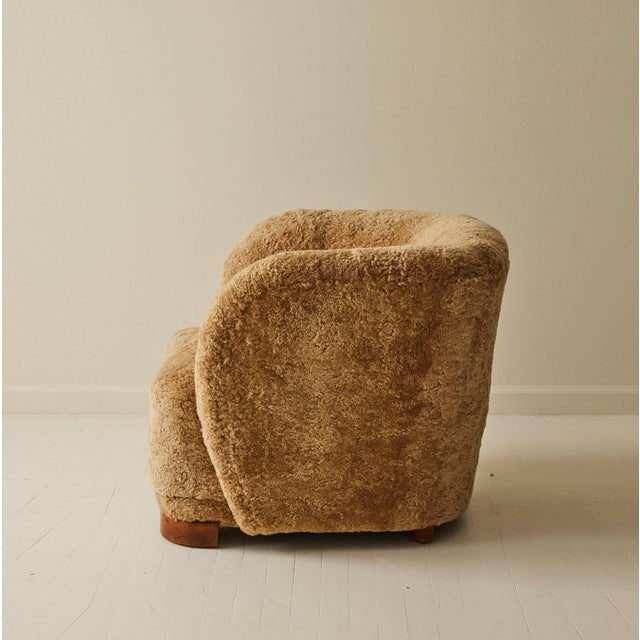 This vintage Danish club chair, newly reupholstered in a honey colored sheepskin, has a generously rounded back and...