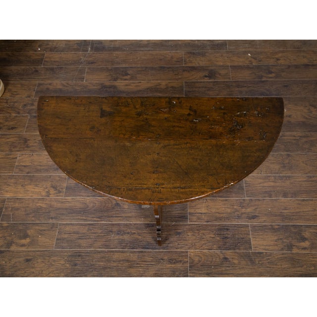 A large Italian Baroque style dark walnut demi lune console table from the 18th century, with semi-circular top, carved...