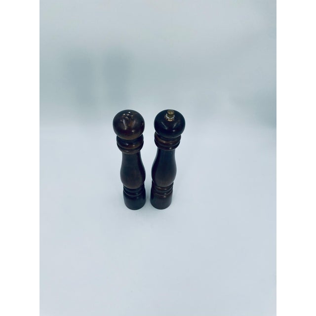 A set of vintage-style salt and pepper mills crafted from dark brown wood. The mills feature a traditional, slim,...