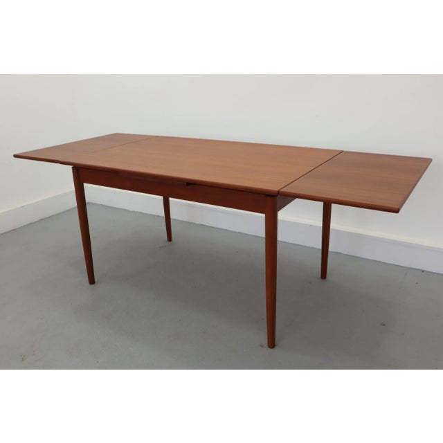 Slim, sleek and very stylish, this 1960s Danish Modern draw leaf teak extending dining table was manufactured by AM Møbler...