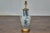 An Asian porcelain vessel table lamp with custom gilt wooden base, wired for the USA. This striking table lamp, crafted...