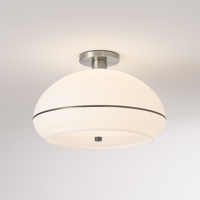 The Morelli Flush Mount is a modern ceiling light featuring a sleek satin nickel steel body and a distinctive black nickel...
