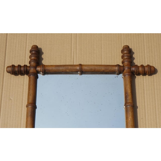 A charming antique English decorative wall mirror, featuring a beautifully turned faux bamboo wooden frame and aged foxed...