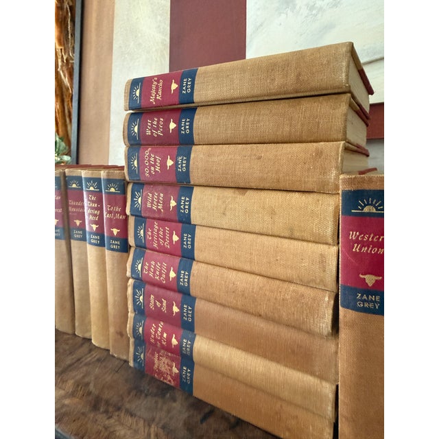 A cohesive and beautifully weathered collection of twenty seven vintage Zane Grey novels, bound in warm tan cloth with...