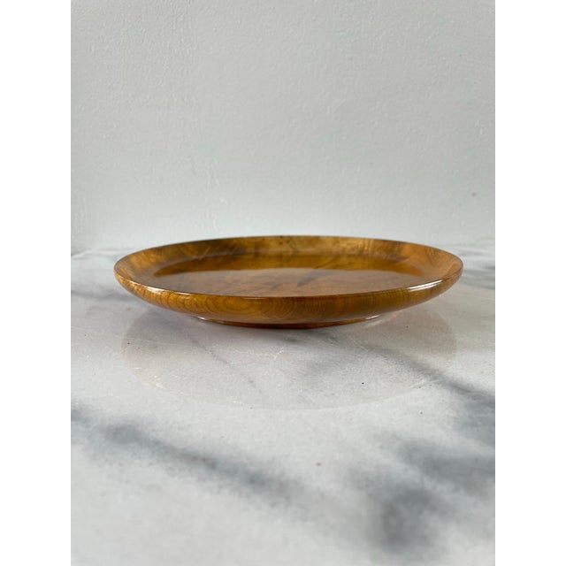 A vintage solid hardwood tray plate with rich golden coloring and a shiny finish.