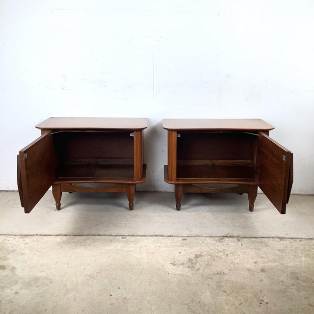 This matching pair of vintage nightstands showcases clean mid-century lines paired with subtle sculptural detail. The low,...