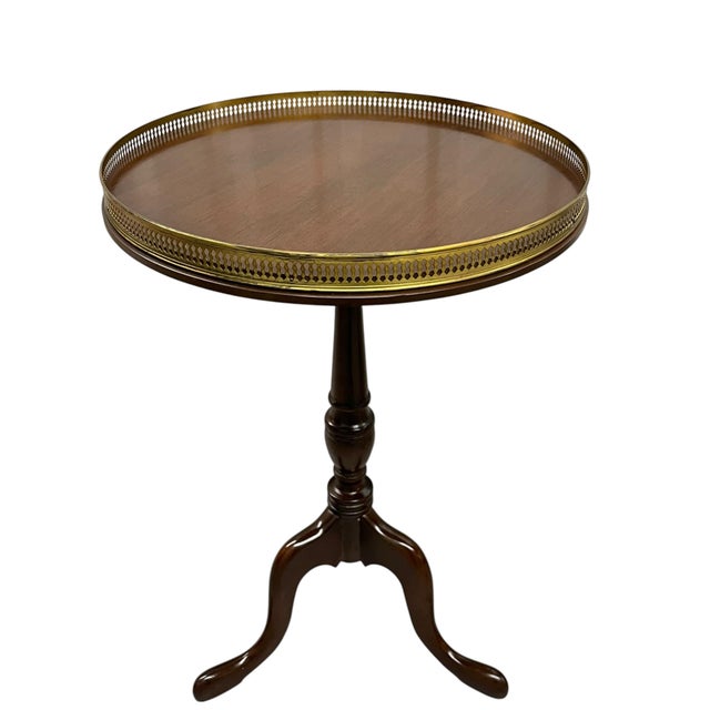 A handsome pair of traditional Chippendale-style side tables featuring elegant tripod bases, turned pedestal supports, and...