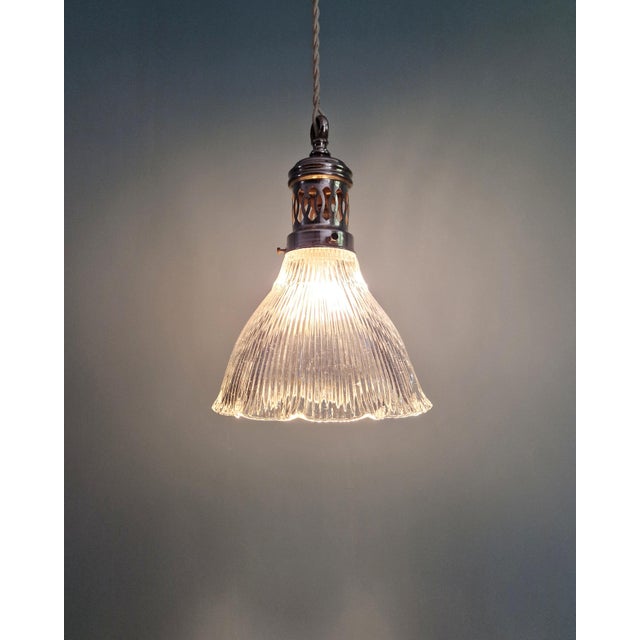 Art Deco pendant light in grooved clear glass with an openwork chrome metal bracket, produced by Holophane in the 1930s....
