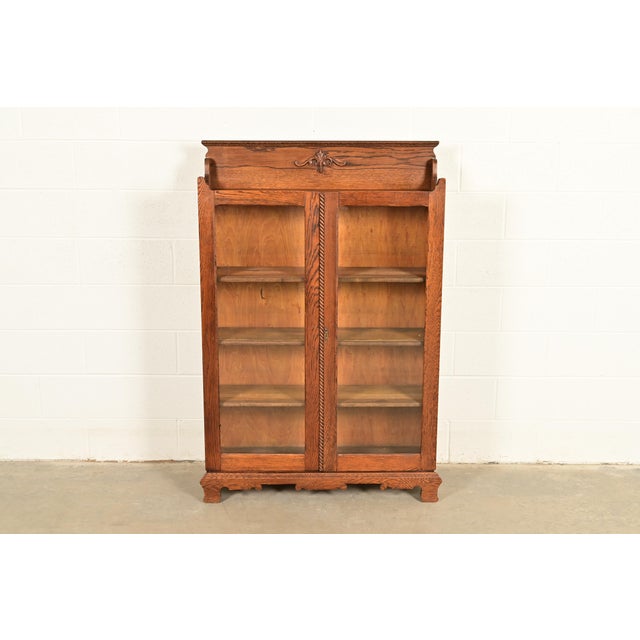 A gorgeous antique Victorian or Arts & Crafts two-door bookcase cabinet By Oliver & Co. USA, Circa 1900 Carved oak, with...