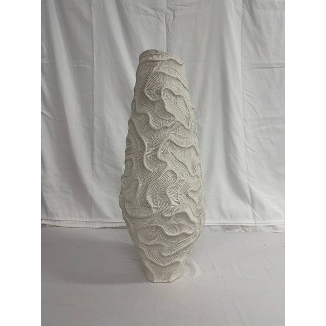 A dense and intricate texture, referring to fossils of madrepores, acts as a skeleton for this vase of Fossilia...