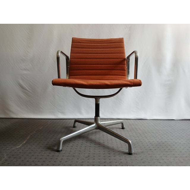 EA 108 swivel, one with armrests, the other without, fabric with brick-colored padding. This piece has an attribution...