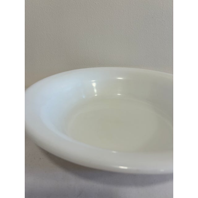 A clean-lined Corning white milk glass serving bowl with a smoothly rolled rim, marked on the underside with the dated...