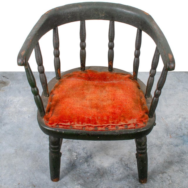 Black wooden Windsor chair with curved back and seat, partially upholstered in red fabric, 19th century.