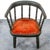 Black wooden Windsor chair with curved back and seat, partially upholstered in red fabric, 19th century.