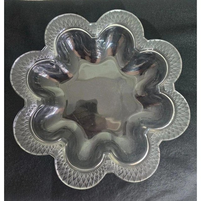 An antique Lalique France moulded glass bowl dating to circa 1910–1920. The bowl features an elegant wavy border with...