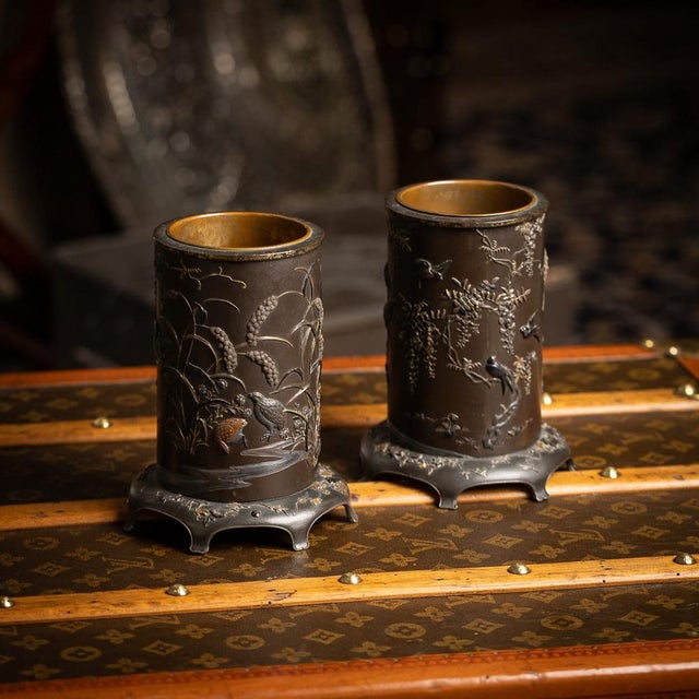 Antique 19th Century Japanese Meiji period pair of inlaid bronze cylindrical brush pots. Each is decorated with a...