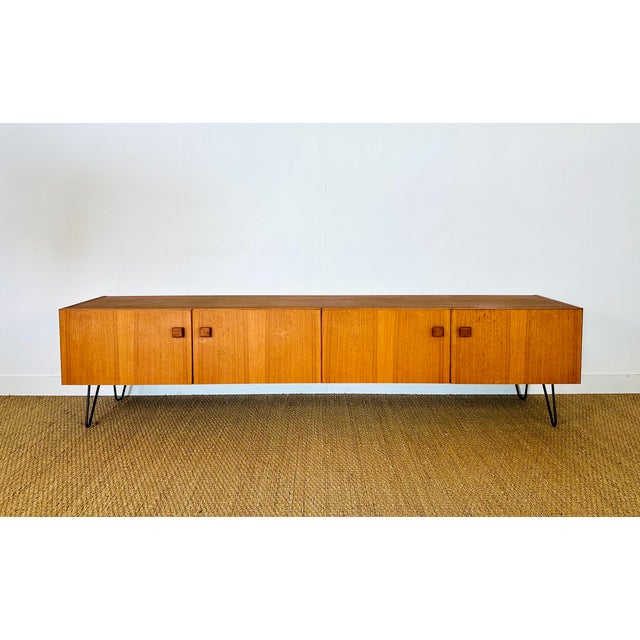 A stunning low sideboard in scandinavian design, dating from the 1960s, crafted from teak wood with warm tones and an...