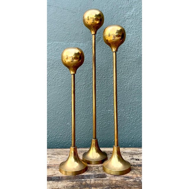 Strikingly sleek and architectural, this set of three vintage brass candle holders exhibits an elongated, minimalist...