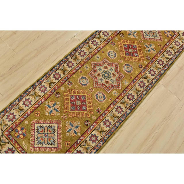 A tribal Caucasian Kazak runner hand-knotted with fine wool on a cotton foundation. This rug features a row of geometric...