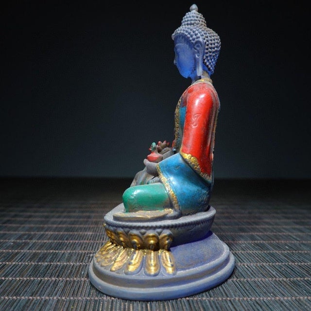 This serene Medicine Buddha (Bhaisajyaguru) figurine is crafted from glass and finished with rich hand-painted polychrome...