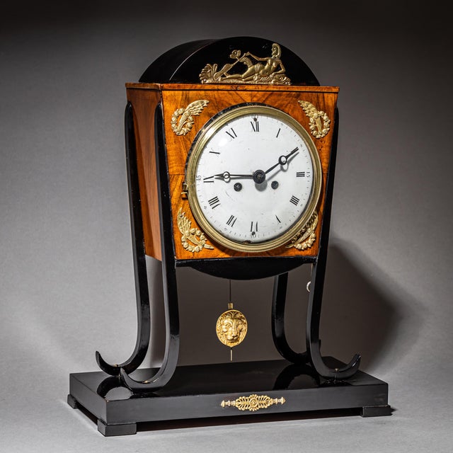Elegant Viennese bracket clock with an ebonized base and splayed legs supporting the clock case. The case is made of...