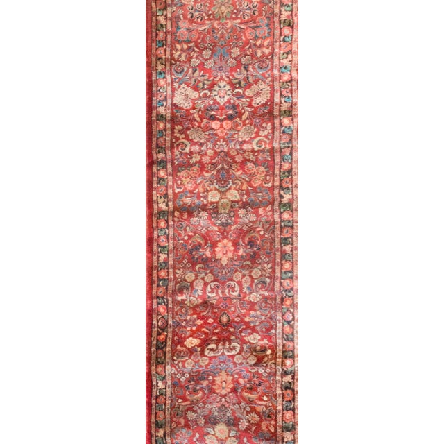 This early 20th-century Persian Sarouk runner features a classic mirrored floral pattern, richly woven in shades of...