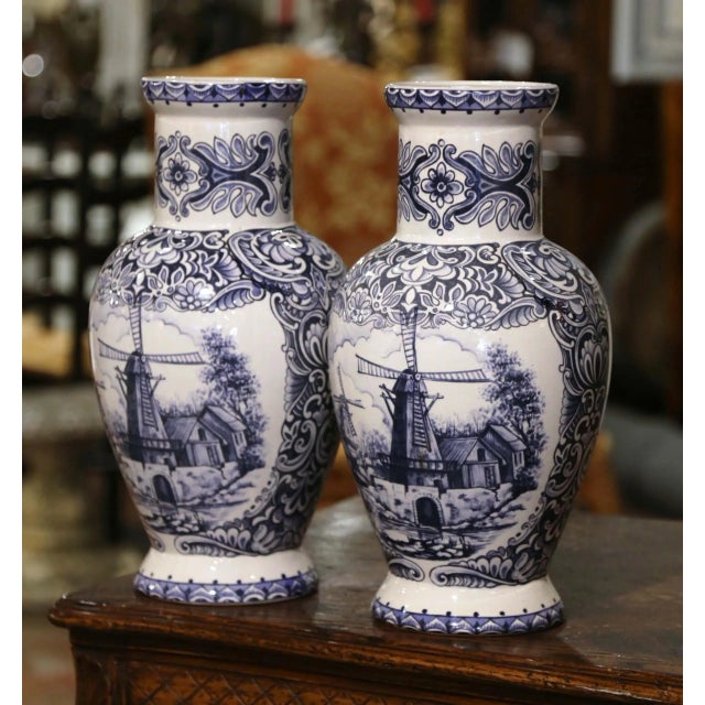 Decorate a shelf or console table with this elegant pair of antique Delft vases. Crafted in Holland circa 1920, both urns...