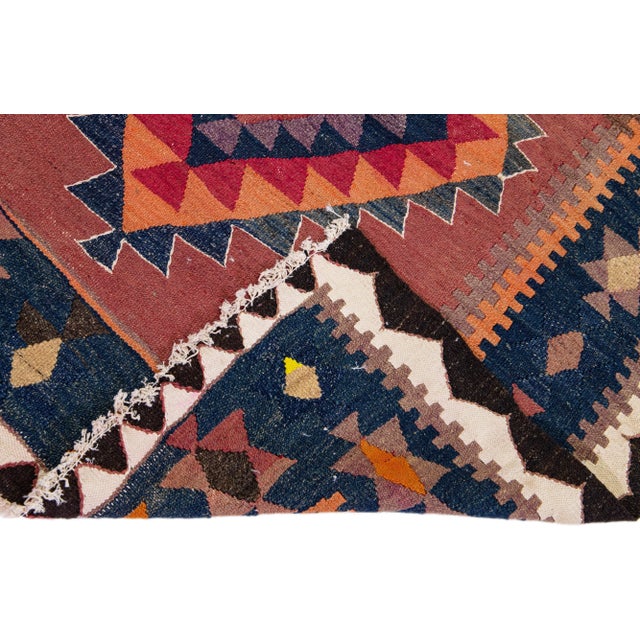 Beautiful vintage Turkish Kilim hand-knotted wool rug with a red field. This piece has a navy blue frame and multicolor...