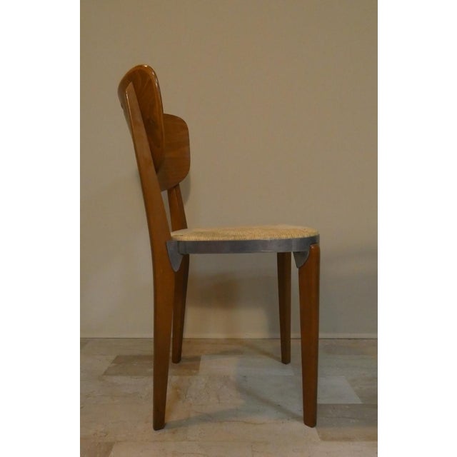 Chair with natural beech structure; curved backrest in polished plywood; seat in die-cast aluminium, straw with knot in...