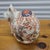 A vintage Japanese Kutani porcelain crouching cat figure, hand-decorated in a traditional Imari-style palette of iron red,...