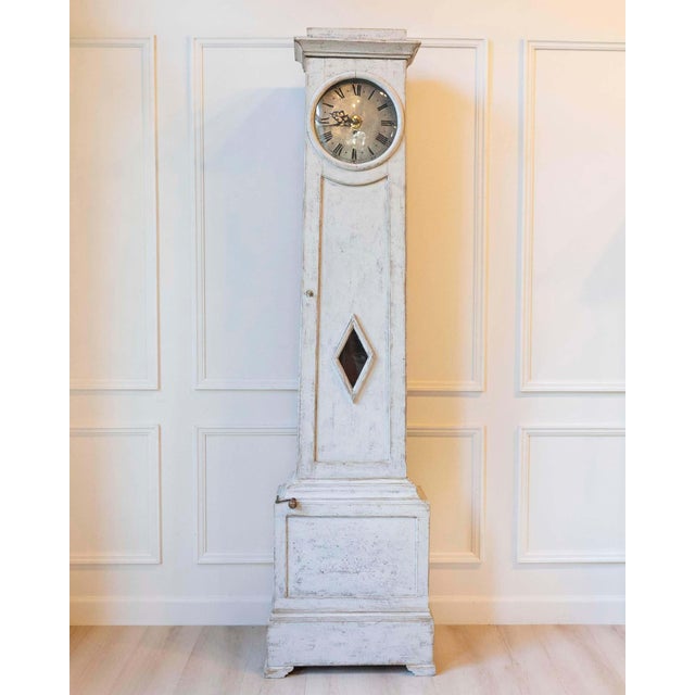 A refined Gustavian longcase clock from around 1800, notable for its elegant shape and well-preserved overall structure....